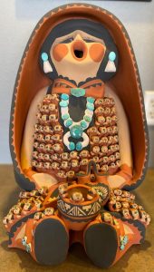 Clay figure of a woman with 112 babies around her at attached to her.